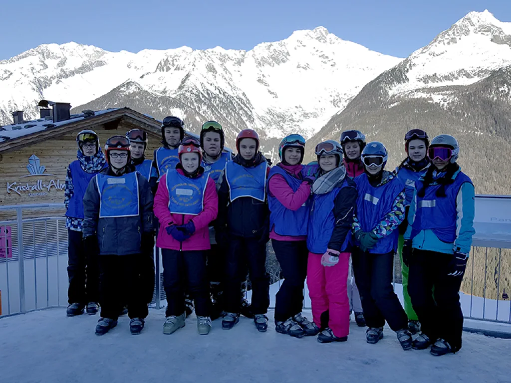 Große Skigruppe steht vor der Bergkulisse.